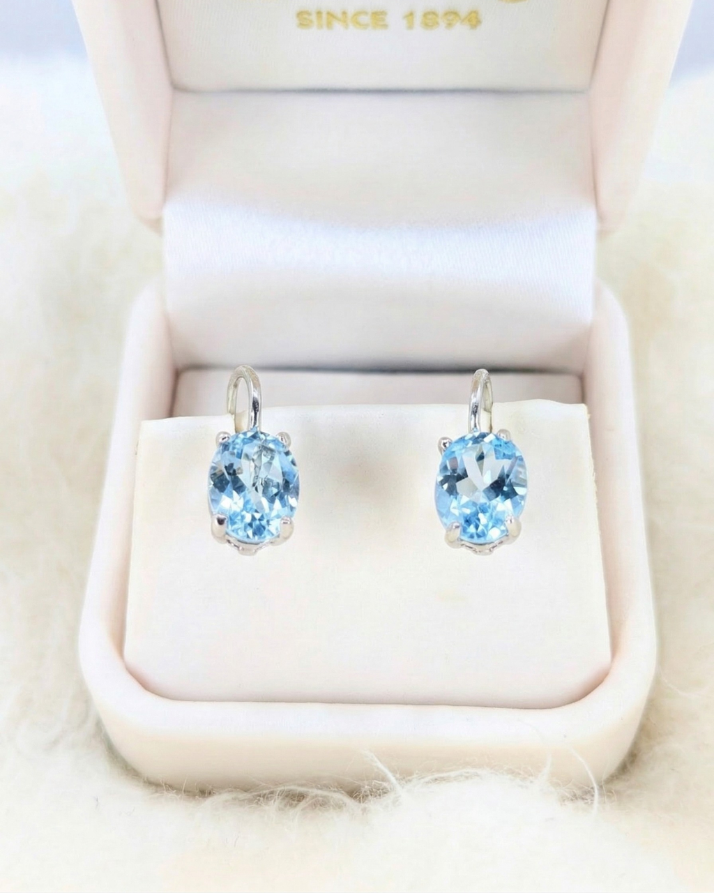 Pair of blue gemstone earrings in a jewelry box with 'Swarovski' branding.