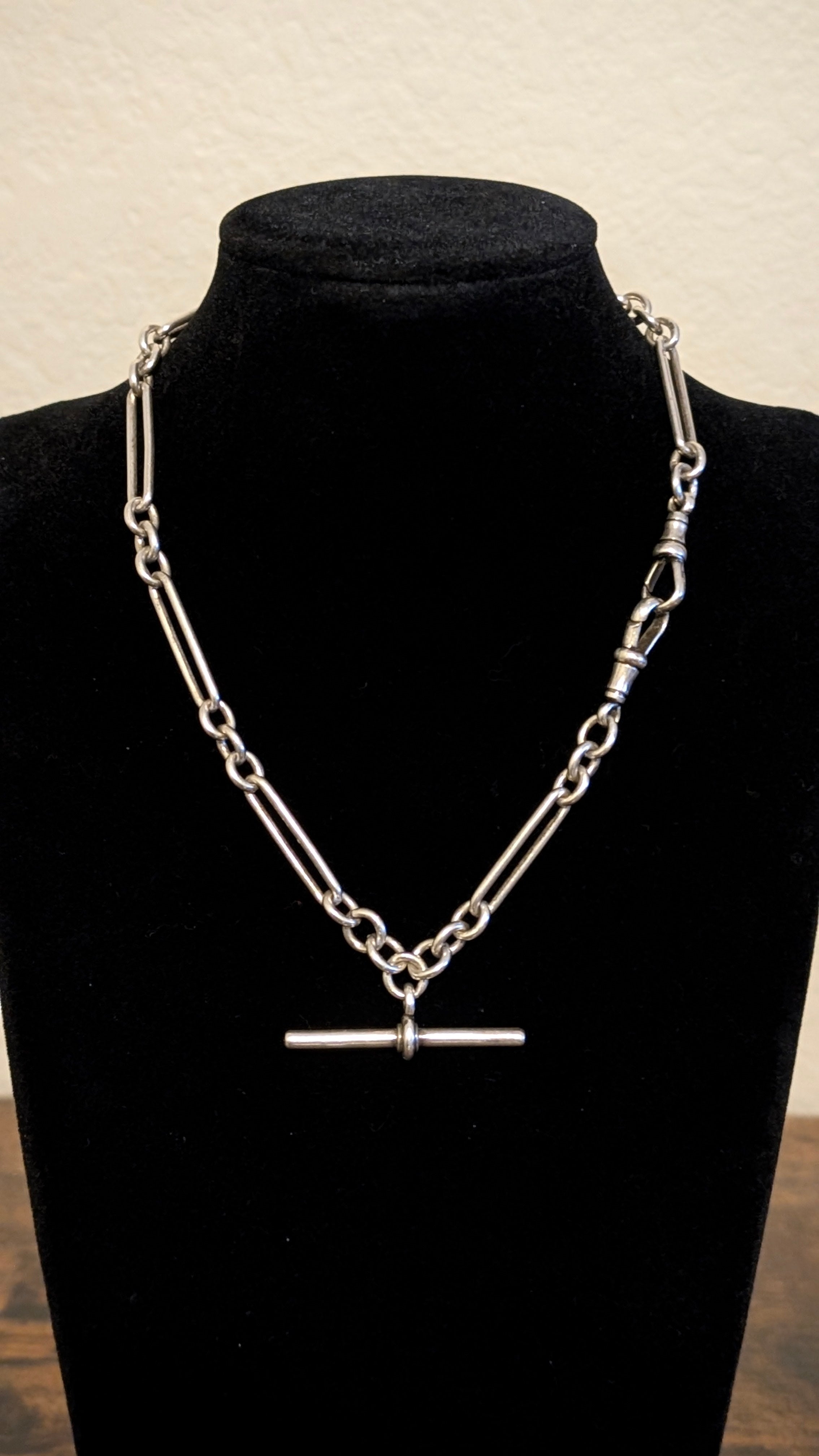 Silver chain necklace on a black mannequin bust against a neutral background