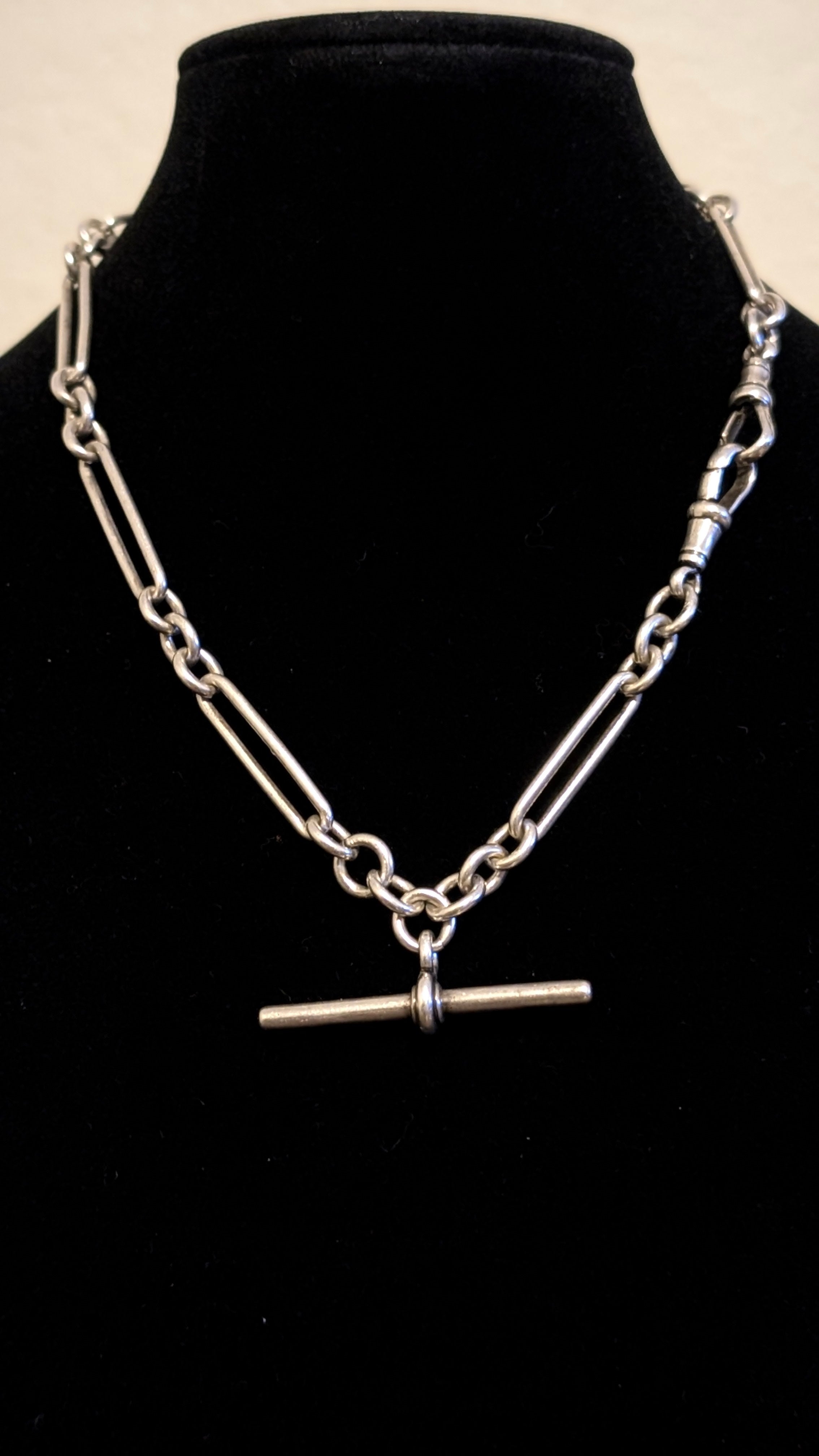 Silver chain necklace with a clasp on a black mannequin bust.