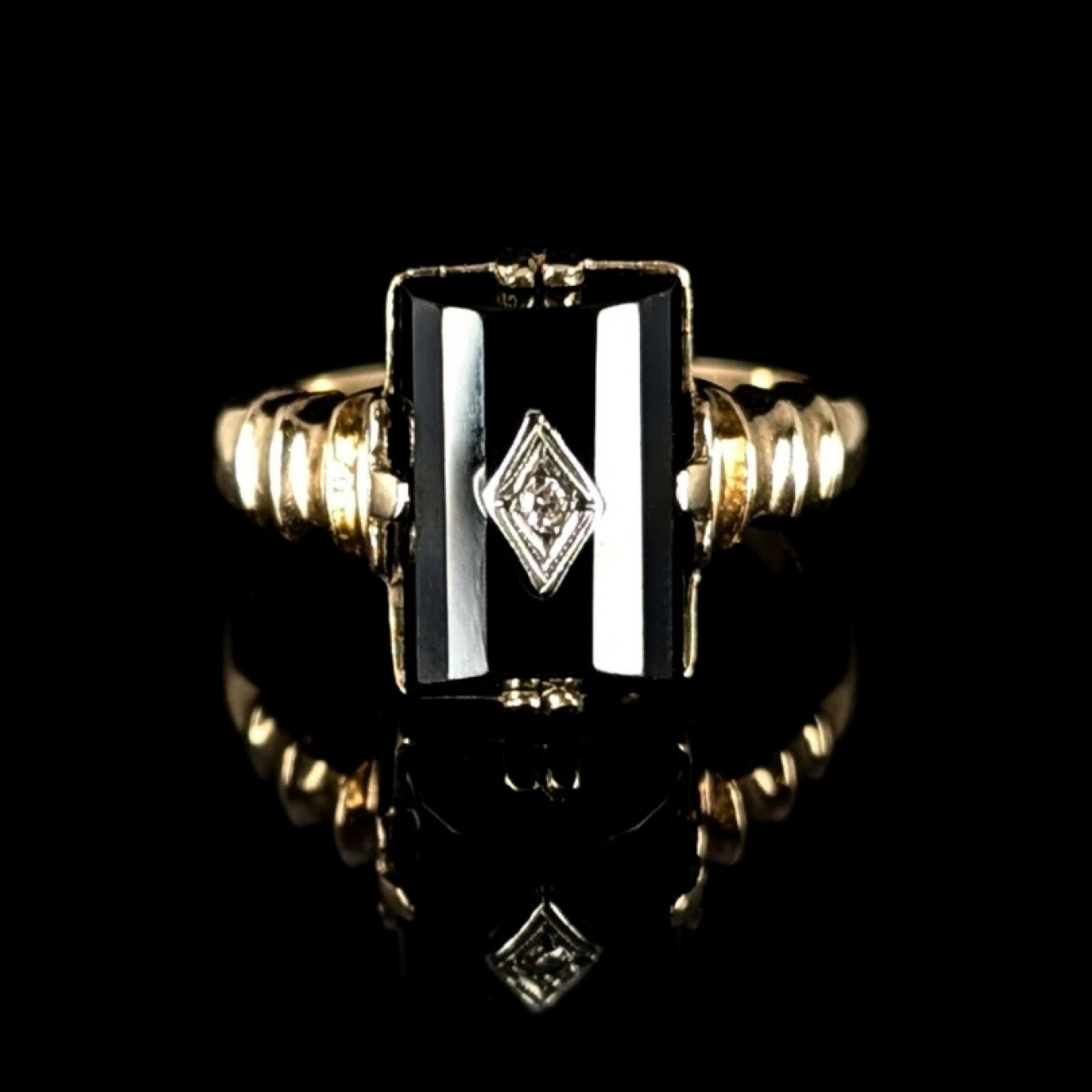 Gold ring with a black stone and diamond design on a black background