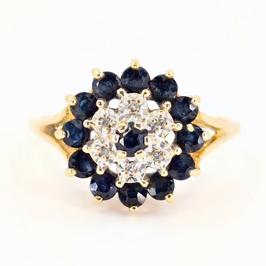 A vintage yellow gold ring with blue sapphires and diamonds forming multiple rows, making it look like a flower of sapphires and diamonds.